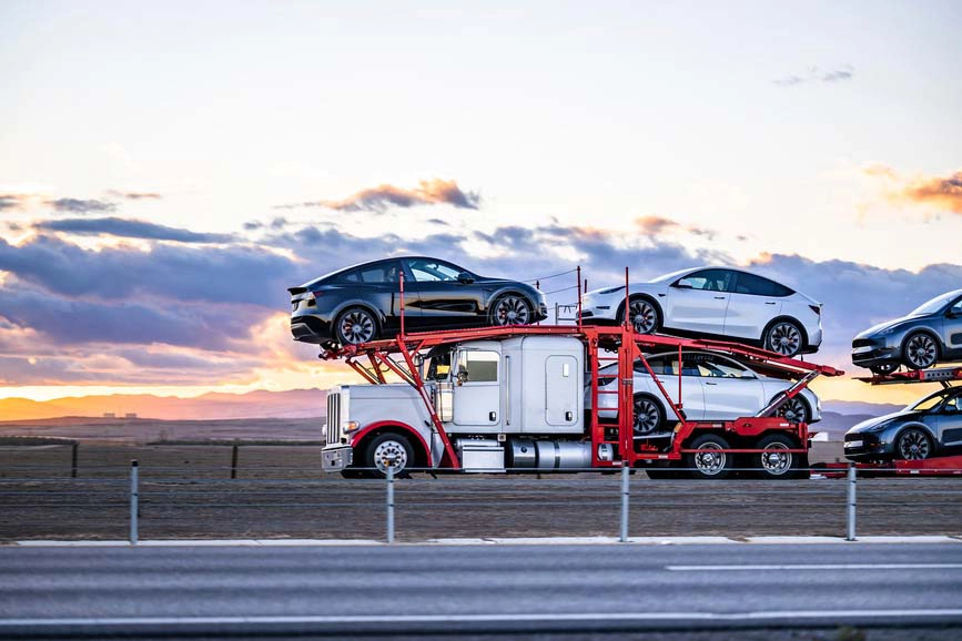 Red and white auto transport truck hauling a vehicle