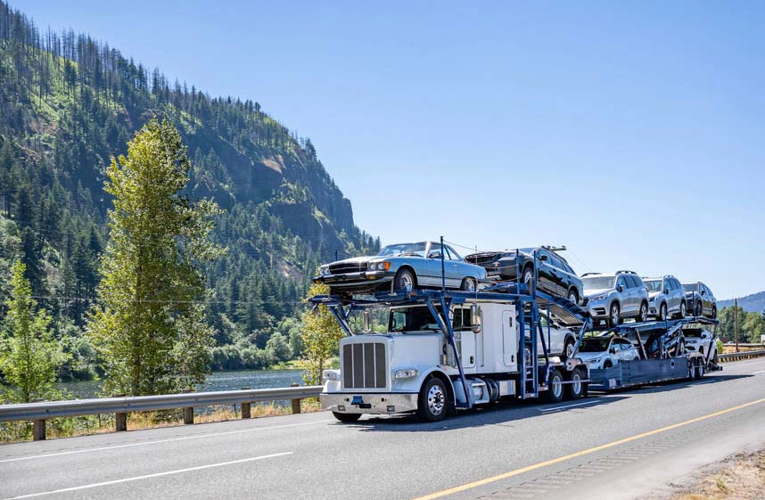 A white auto transport truck driving through a canyon.